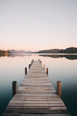 Fototapeta premium Wooden Dock Extending into Calm Lake at Sunset