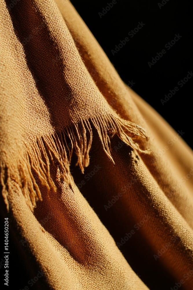 Poster warm brown shawl fabric with fringe, creating texture pattern on black background