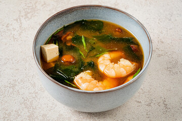 Tasty shrimp and tofu soup with fresh greens and spices in a cozy kitchen