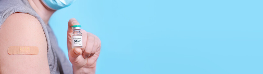 Man with a bottle of vaccine and a plaster on his shoulder after getting vaccine for DTaP...