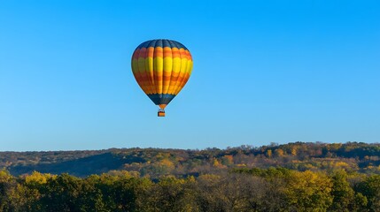 Obraz premium A hot air balloon ascending into a clear blue sky over rolling hills