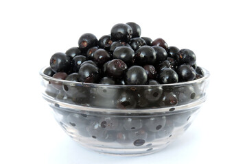 Fresh ripe aronia berries decorated in a glass bowl, white background, side view