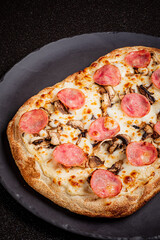 A freshly baked pepperoni and mushroom pizza awaits on a dark stone plate