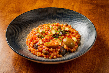 A warm bowl brimming with a savory grain mix, vibrant vegetables, and a sprinkle of herbs