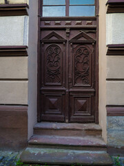 Detailed brown wooden door with carvings on historic building in Ivano-frankivsk