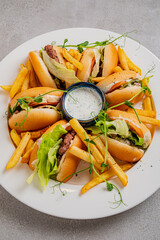 A colorful platter of hot dogs in soft rolls, served with golden fries and fresh greens