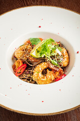 Shrimp on savory noodles, topped with fresh greens and bright peppers, invites indulgence