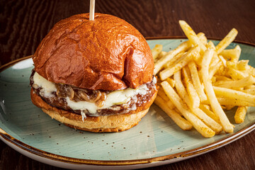 Juicy gourmet burger topped with melted cheese and caramelized onions, served with crispy fries