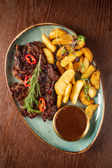 A tempting display of grilled steaks, golden potatoes, and a rich dipping sauce awaits