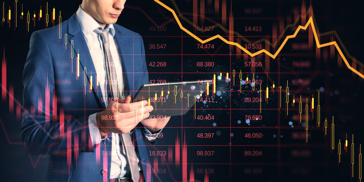 Businessman analyzing financial data on digital tablet with stock market graphs and candlestick charts in technology-driven background concept.