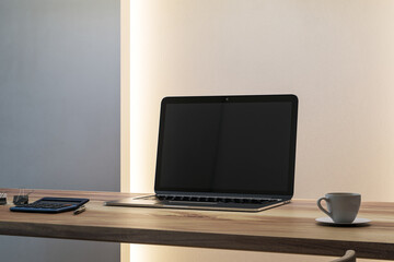 Modern workspace mockup with blank laptop screen on wooden desk in softly backlit interior office room setting for clean presentation design. 3D Rendering