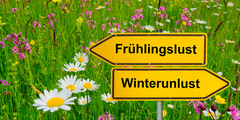 Ein Wegweiser zeigt in unterschiedliche Richtungen mit der Aufschrift Frühlingslust und...