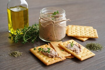 Delicious spread on crackers with herbs and olive oil on wooden table