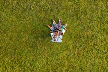 Aerial view with young women lying down and relaxing at a picnic in the sunset light