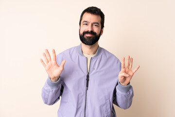 Naklejka premium Caucasian man with beard wearing a jacket over isolated background counting nine with fingers