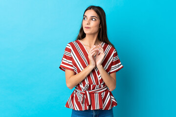 Young caucasian woman isolated on blue background scheming something