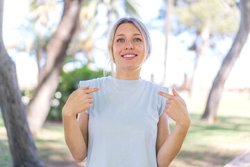 Young blonde woman at outdoors with surprise facial expression
