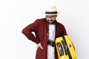 Traveler man man with beard holding a suitcase over isolated white background suffering from...