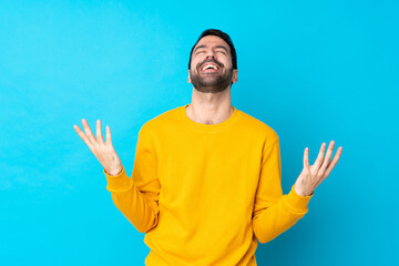 Young caucasian man over isolated blue background smiling a lot