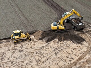 Excavator and bulldozer on a construction site, loads earth onto a tractor with dump truck, civil...