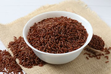 Raw brown rice in bowl on burlap