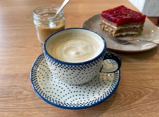 Cup with aromatic cappuccino and tasty dessert on a table in a cafe