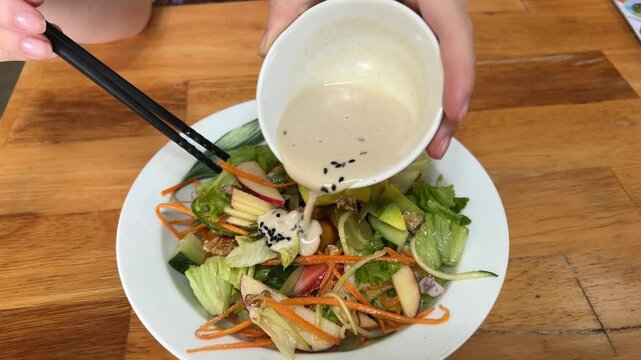 Fresh salad with vegetables, dressing pouring over for vibrant taste