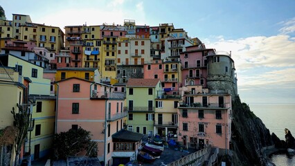Colorful hillside buildings of Manarola stacked tightly along a rocky cliffside overlooking the sea in an old coastal village.
