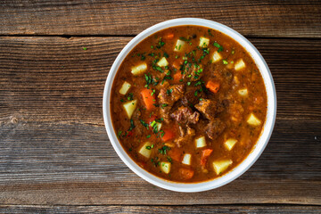 Beef vegetables goulash soup on wooden table
