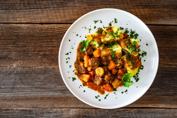 Beef vegetables goulash with potatoes on wooden table