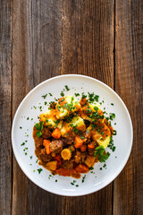 Beef vegetables goulash with potatoes on wooden table