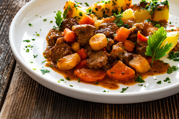 Beef vegetables goulash with potatoes on wooden table