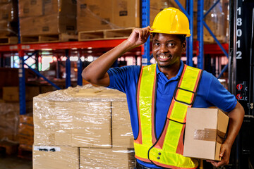 A confident warehouse worker holding a cardboard box in a storage warehouse. 