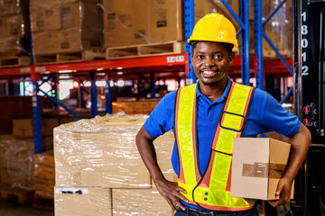 A confident warehouse worker holding a cardboard box in a storage warehouse. 