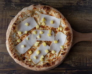 Overhead view of pizza with sliced meat and cubed cheese on wooden board