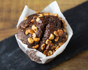 Close up of a chocolate muffin with nuts on a black slate surface