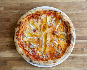 Overhead shot of a brie pizza on a white plate on a wooden surface