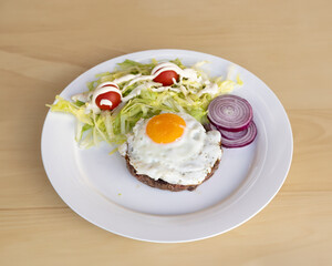 Ground beef patty with fried egg and salad for home-style lunch visuals
