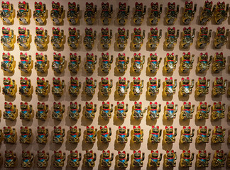 Wall showing many golden waving lucky cats bringing fortune and happiness