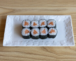 Salmon maki sushi rolls on white plate for traditional Japanese food visuals
