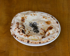 Traditional Indian naan bread with nigella seeds served on white plate for ethnic food concepts