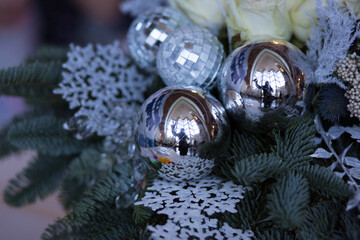 A detailed close up of a beautifully arranged Christmas display featuring shiny silver balls and intricate snowflakes as decoration