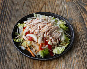 Overhead shot of a chicken salad on a black plate with wood background