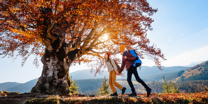 Couple of young tourists are walking in the mountain forest. Beautiful mountain panorama landscape background.