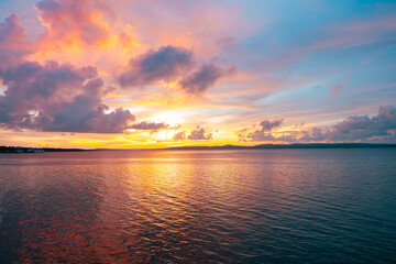 Gentle sea waves meet a vibrant sky where sunset blends orange and pink into deep blue twilight.