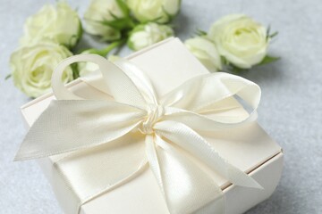 Beautiful white roses with gift box on gray background
