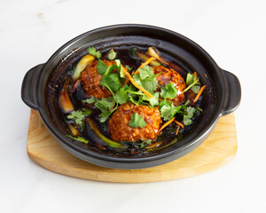 Close up of meatballs with cilantro in a black bowl on wood surface