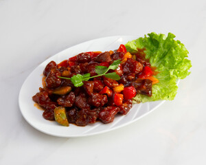 Plate of beef stir fry with bell peppers and lettuce on white table
