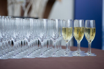 A beautiful row of elegant champagne glasses are meticulously lined up on a stylish table, ready...