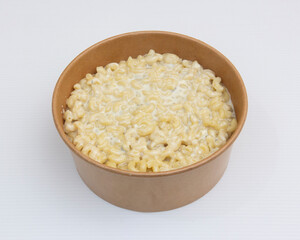 A bowl of creamy macaroni and cheese on a white background surface